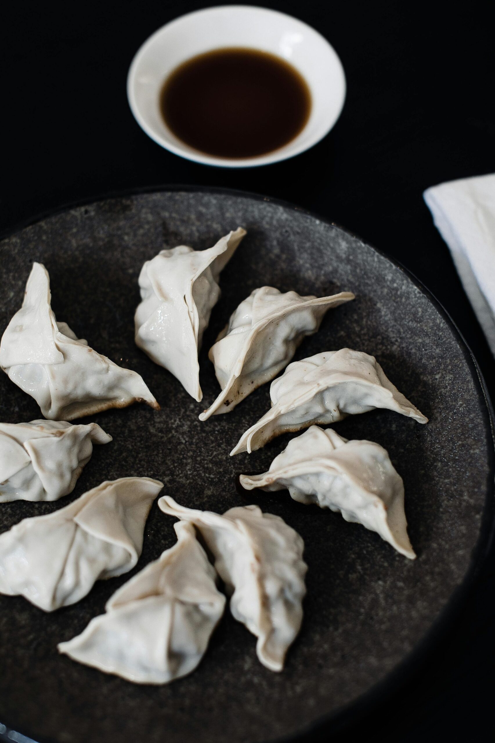 pexels-photo-4846376-4846376 From above of ceramic plate with tasty Japanese dumplings gyozas with bowl of sauce on black table
